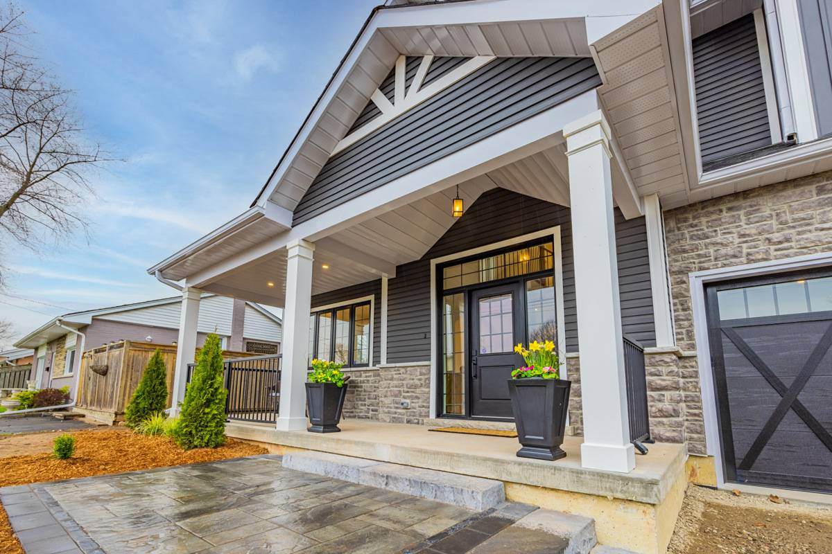 The charming exterior of an Ontario home with a welcoming front porch, stone accents, and landscaped walkway | Ever After Homes