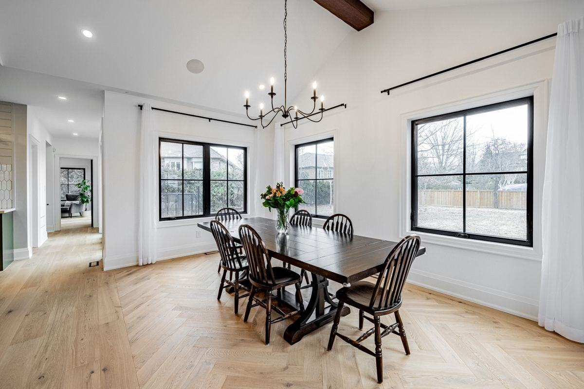 A dining area with vaulted ceilings, a dark wood table, and black spindle chairs, illuminated by a modern black chandelier. | Ever After Homes